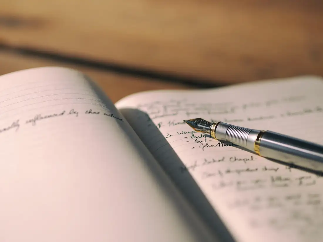 A fountain pen resting on an open handwritten notebook, practising the hard parts of Thai