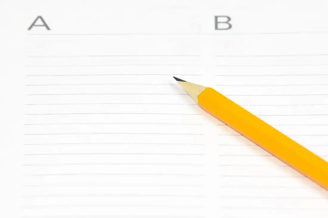 A pencil resting on lined paper ruled into two labelled columns