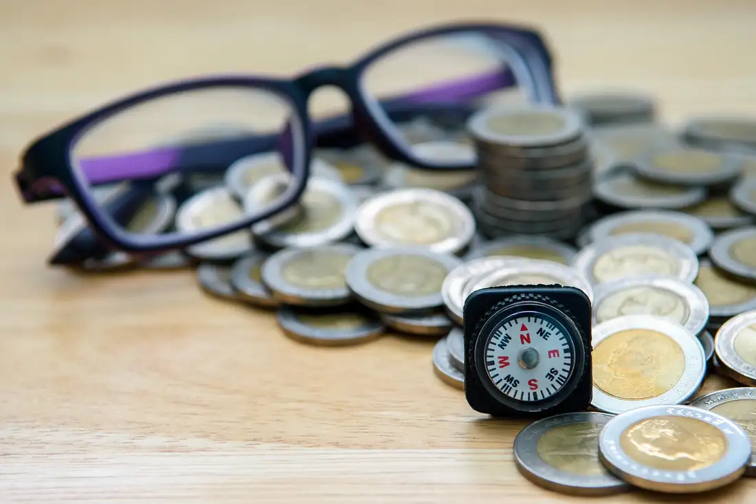A pile of Thai baht coins with reading glasses, the real cost of Thai language school