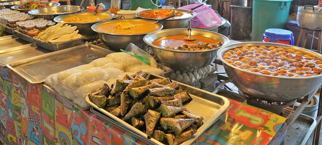A Thai street food stall with curries, banana-leaf parcels and rice noodles